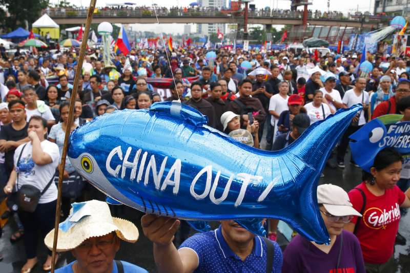 圖為反對中國擴張南海霸權的菲律賓民眾，在馬尼拉的國會大廈外群聚抗議。示威者高舉一個鯊魚氣球，上頭寫著「中國滾蛋」。（資料照，美聯社）